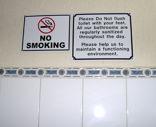 Belize City, flush toilet with feet sign